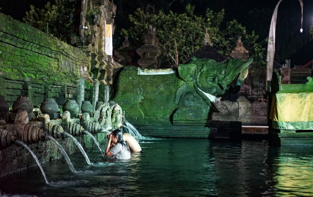 A couple doing Balinese Water Purification process under moonlight