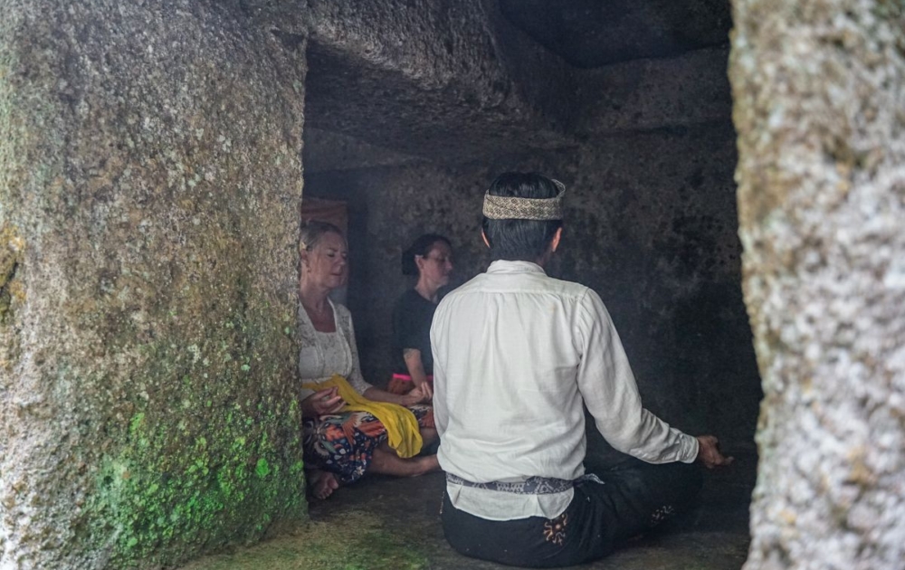 Two females following a guided Balinese mediation inside ancient cave near Ubud Bali
